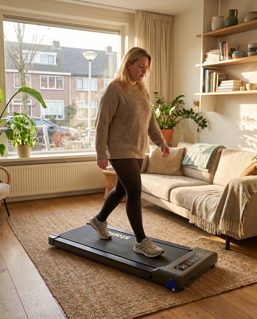 Vrouw loopt 's avonds rustig op de Stane-loopband in een warme woonkamer