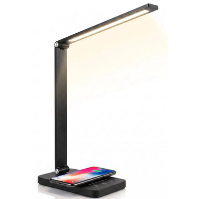 De Stane bureaulamp met één LED-arm op een witte achtergrond; op de voet ligt een telefoon draadloos te laden.