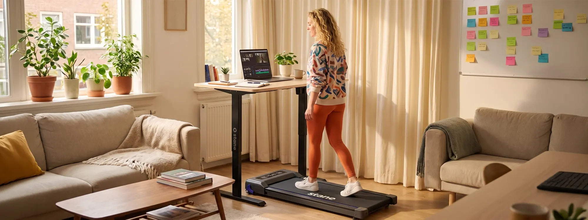 Thuiswerker wandelt ontspannen op de Stane loopband in een warme, lichte woonkamer met daglicht